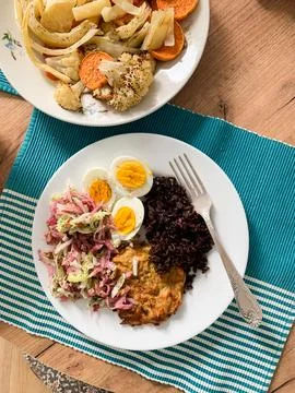 A plate features brown rice, boiled eggs, zucchini pancakes, and fresh sala.. Stock Photos