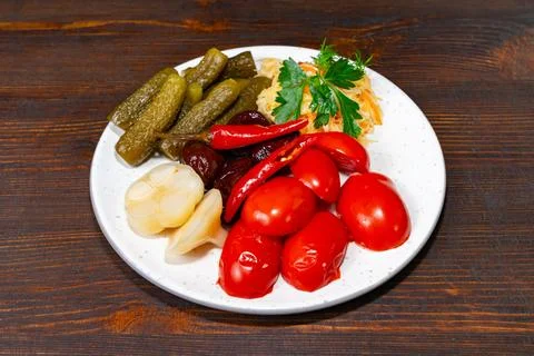 A plate features a colorful array of pickled vegetables including cucumbers Stock Photos