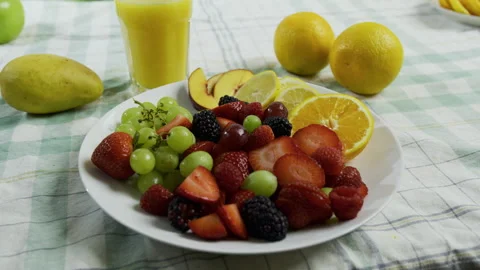 Plate filled with delicious fruit near cup of orange juice - tracking shot Stock Footage 341027341