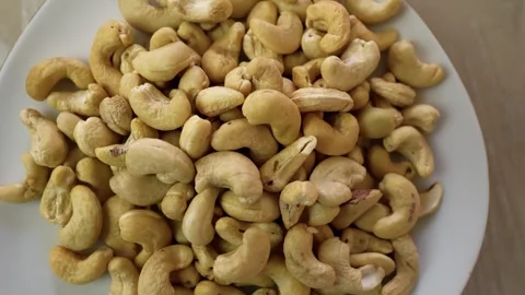 Plate filled with raw cashew nuts on a wooden table Stock Footage 320726935