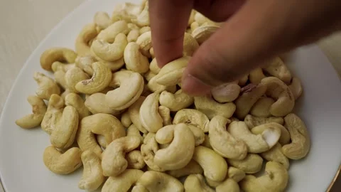 Plate filled with raw cashew nuts on a light background Stock Footage 320726957