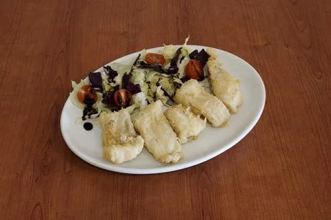A plate of fish with a side of salad Stock Photos
