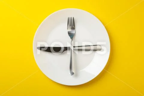Plate with fork and knife on yellow background, top view Stock-Fotos
