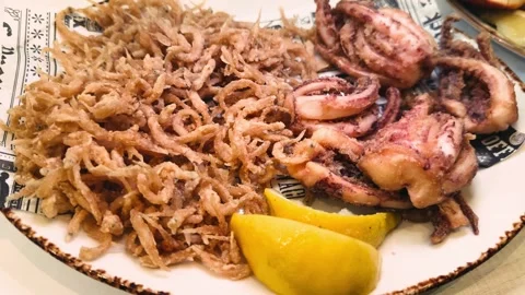A plate of freshly fried elvers, young eels, served alongside crispy fried squid Stock Footage 330796015