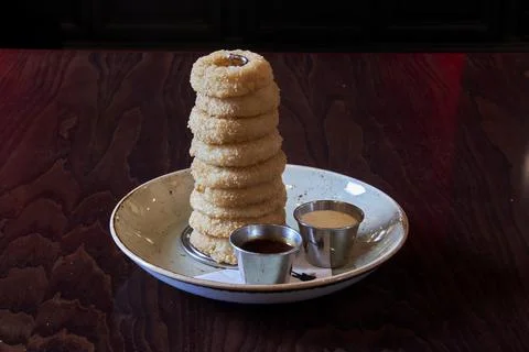 A plate of fried dough with a stack of doughnuts on top Stock Photos