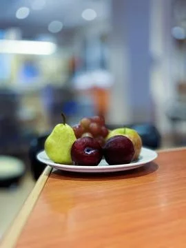 A Plate of fruit on the table with a blurred background. Stock Photos
