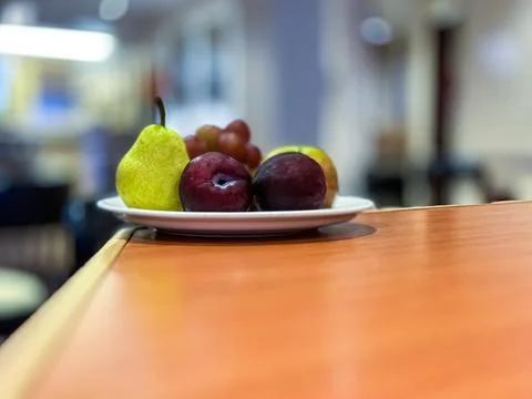 A Plate of fruit on the table with a blurred background. Stock Photos
