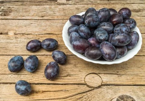 Plate full of fresh plums on a wooden background Stock Photos