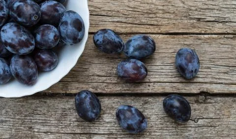Plate full of fresh plums on a wooden background Stock Photos