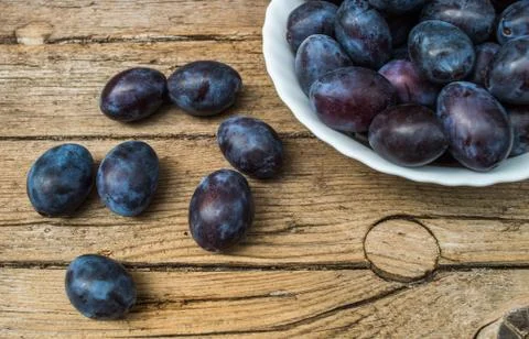 Plate full of fresh plums on a wooden background Stock Photos