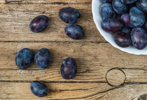 Plate full of fresh plums on a wooden background Stock Photos