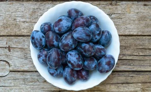 Plate full of fresh plums on a wooden background Stock Photos