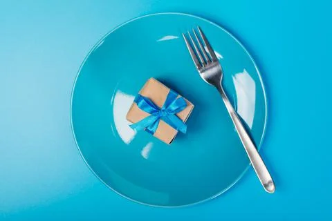 Plate with gift and fork. An empty plate with a small box is a gift. Stock Photos