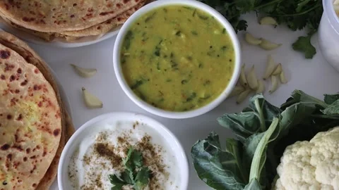 A plate of Gobi paratha with dal fry and curd in bowls, surrounded by cauli.. Vídeo Stock 302580341