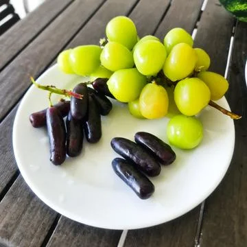 A plate of grapes on a table Stock Photos