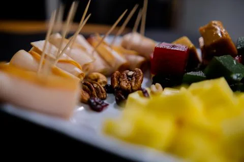 Plate of ham rolls, fruit paste, cheese cubes, and nuts with blurry background Stock Photos