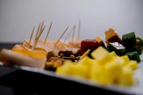 Plate of ham rolls, fruit paste, cheese cubes, and nuts with white background Stock Photos