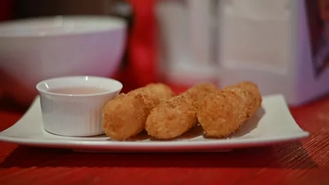 A plate holds several crispy fried snacks alongside a small bowl of dipping Stockbeeldmateriaal 336778479