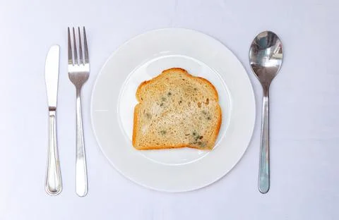 A plate holds a slice of bread, a carrot, and a piece of jelly. The utensils  Stock Photos