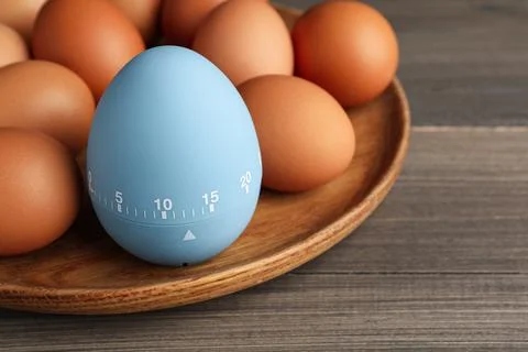 Plate with kitchen timer and chicken eggs on wooden table, closeup Foto stock