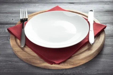 Plate, knife and fork on rustic background Stock Photos
