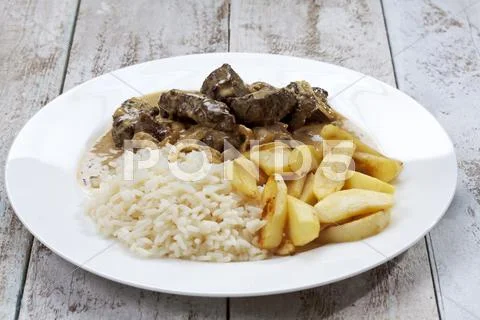 Plate with liver of beef, rice, apple wedges on white wooden table, studio shot Stock Photos