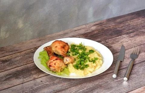 A plate of mashed potatoes and two baked chicken legs on a lettuce leaf on .. Stock Photos