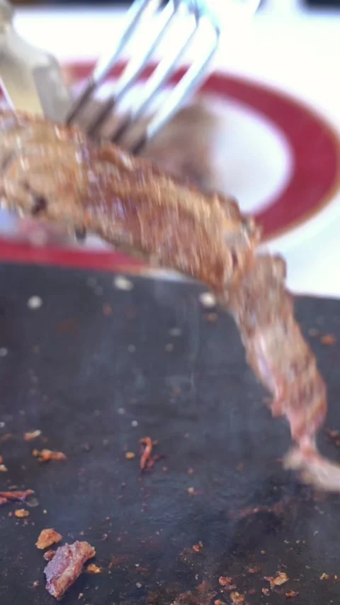 A plate of meat is on a black surface with a red plate behind it Stock Footage 327529311