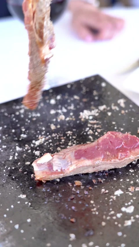 A plate of meat with a fork on it. The meat is cut in half and has salt on it Stock Footage 327529305