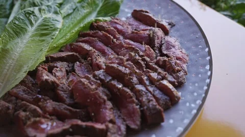 A plate of meat with a leafy green on top Stock Footage 297872083