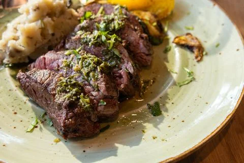 A plate of meat with a side of mashed potatoes and vegetables Stock Photos