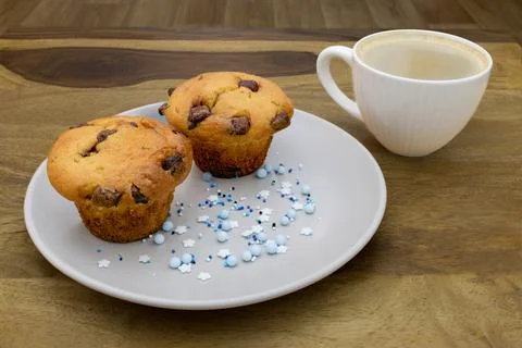 A plate of muffins and a cup of coffee sit on a table Stock Photos