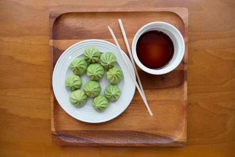 A plate of multiple Dim Sum dumplings and a bowl of soy sauce with chopsticks Stock Photos