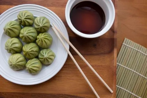 A plate of multiple Dim Sum dumplings and a bowl of soy sauce with chopsticks Stock Photos