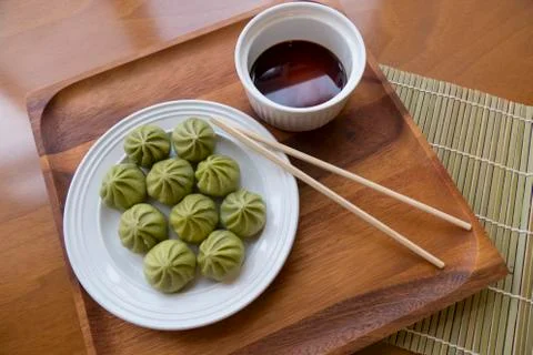 A plate of multiple Dim Sum dumplings and a bowl of soy sauce with chopsticks Stock Photos