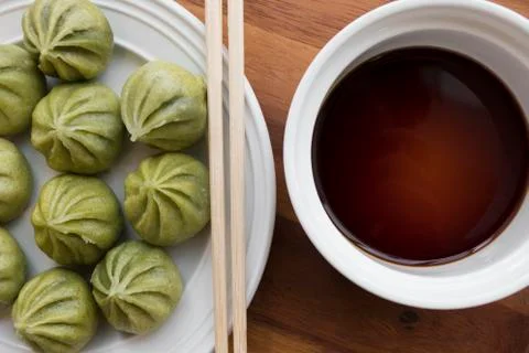 A plate of multiple Dim Sum dumplings and a bowl of soy sauce with chopsticks Stock Photos