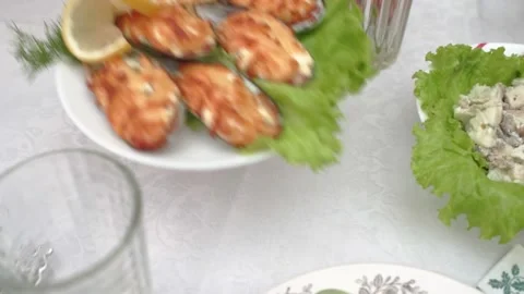 Plate with mussels is placed on table with tablecloth by woman's hands. HD Stock Footage 141446517