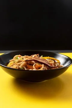 Plate with noodles on a bright yellow background. Stock Photos