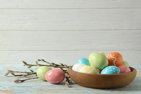 Plate with painted Easter eggs on table against wooden background, space for  Foto stock
