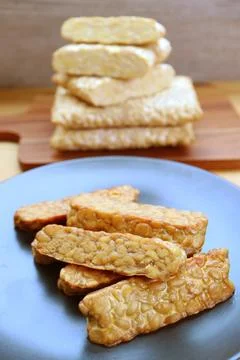 Plate of pan fried Tempeh with Stack of the Uncooked in the Backdrop 스톡 사진
