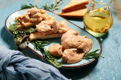 Plate with pieces of tasty cod liver and herbs on blue wooden background, clo Stock Photos