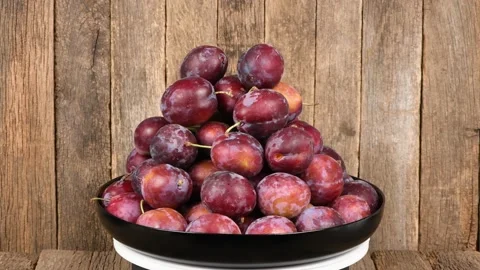 Plate of plums on wooden background. Loop motion. Side view. Stock Footage 161316356