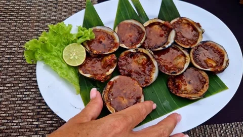 On the plate is a prepared dinner of baked shellfish with vegetables and herbs Stock Footage 263206135