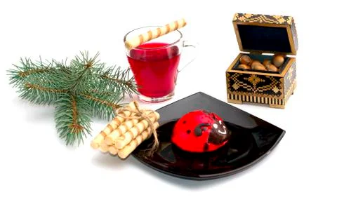 Plate with red cake, tea, nutlets and a coniferous branch Stock Photos