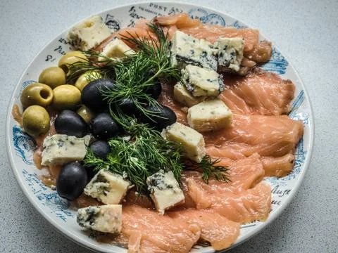 Plate with red fish appetizer with cheese, olives and parsley Stock Photos