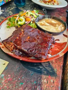 A plate of ribs with a side of mashed potatoes and a salad Stock Photos
