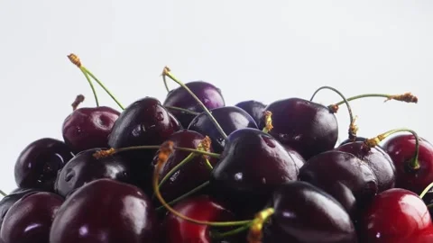 On a plate of ripe dark red cherries rotating in a circle on a white backgr.. Stock Footage 294704243