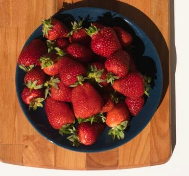 Plate of ripe strawberries on a wooden background Stock Photos