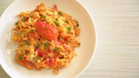 Plate of scrambled eggs with tomatoes and herbs on white dish Stock Photos