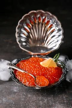 Plate in shape of seashell with delicious red caviar on dark table, closeup Stock Photos